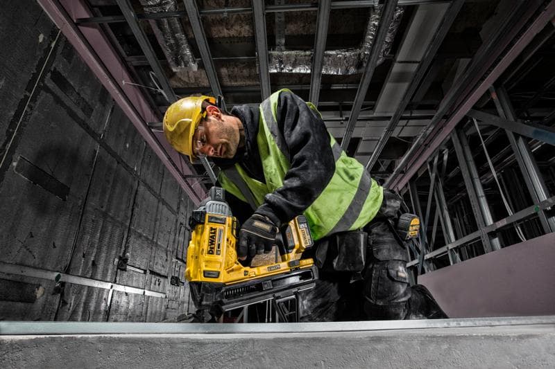 Operário usa DEWALT DCN890P2 em obra, com capacete e colete de segurança.