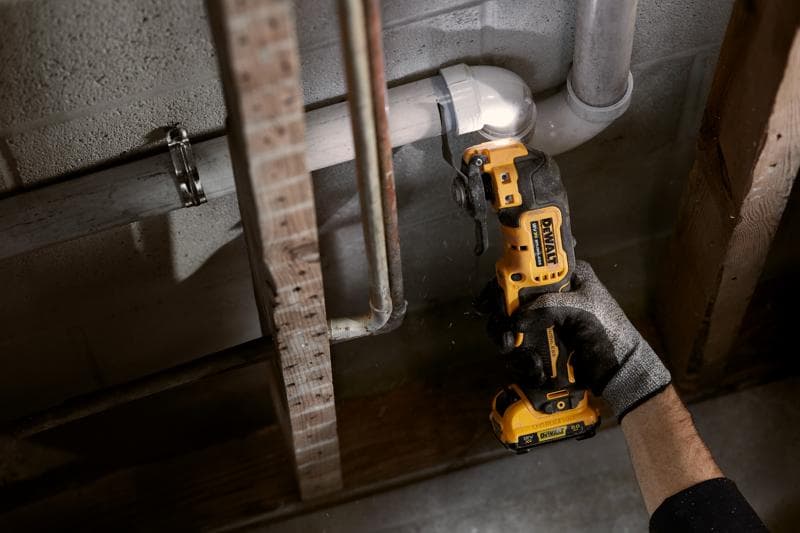 Pessoa usa ferramenta oscilante DEWALT sem fio para cortar tubo junto a parede de concreto.