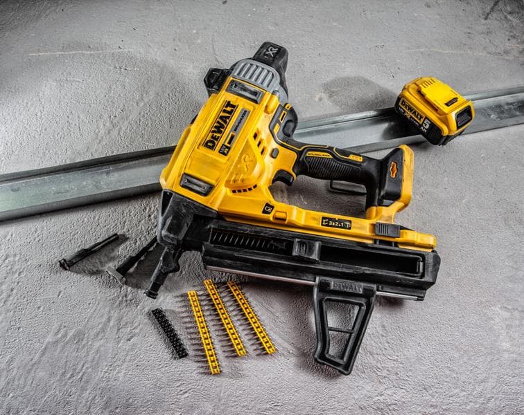Pistola de pregos DEWALT DCN890P2 com acessórios e fixadores sobre superfície de concreto.