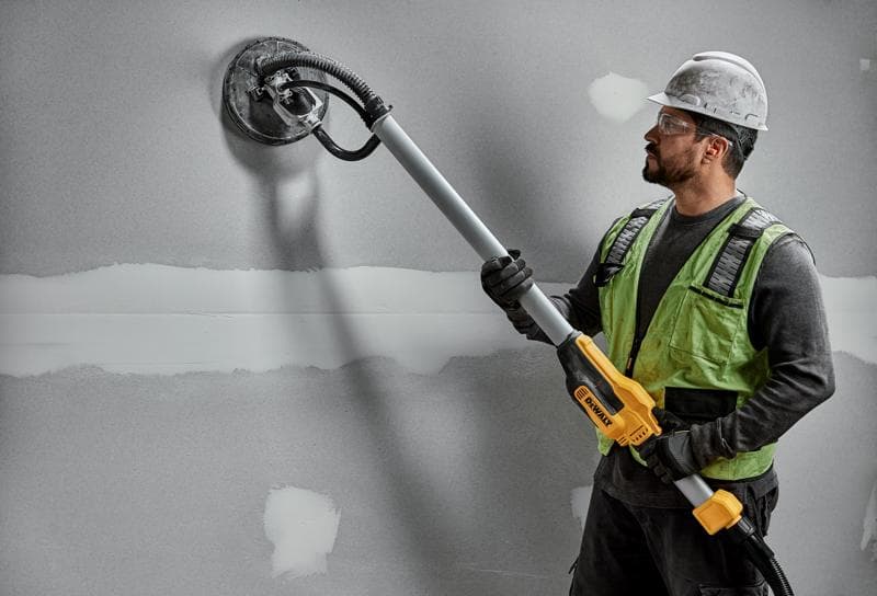 Funcionário usa lixadeira DEWALT DWE7800, DWE7800-QS em parede de drywall. Produto de fotografia.