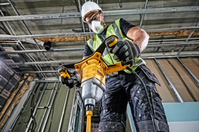 Pessoa utiliza misturador DEWALT DWD241 em obra, com colete e luvas de segurança.