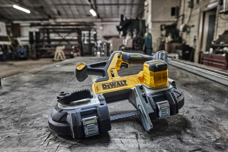 DEWALT cordless band saw placed on a workbench in an industrial workshop setting.