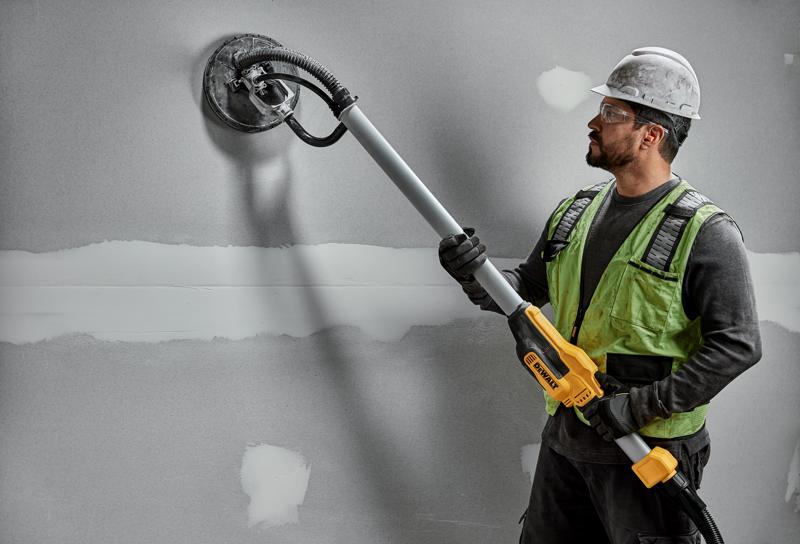 Funcionário usa lixadeira DEWALT DWE7800, DWE7800-QS em parede de drywall. Produto de fotografia.